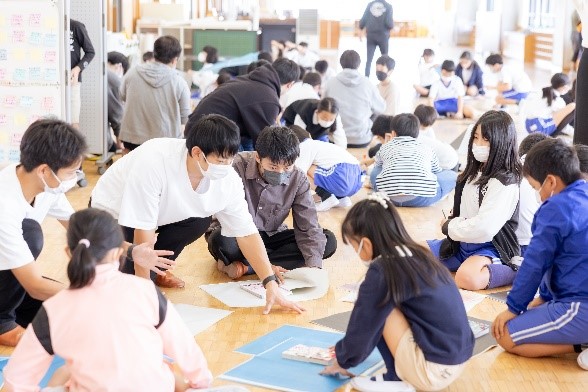 古紙を活用した工作を行う学生と児童【黒笹小学校】

